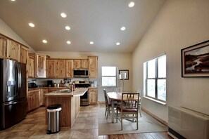 A modern kitchen with wooden cabinets, stainless steel appliances, and a dining area with a view of the outdoors. - Upper Level Ranch Accommodation for Glamping in Montana (Whitehall)