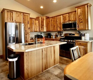 Una cocina con armarios de madera, electrodomésticos de acero inoxidable, una isla central y un bote de basura.