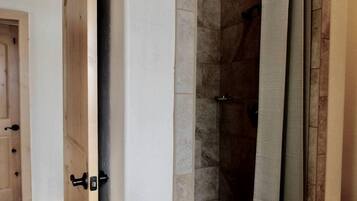 Een douche met een glazen deur, een handdoekhouder en een deurklink.