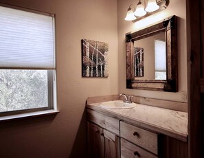 A bathroom with a window, a sink, a mirror, and wall art. - Upper Level Ranch Accommodation for Glamping in Montana (Whitehall)