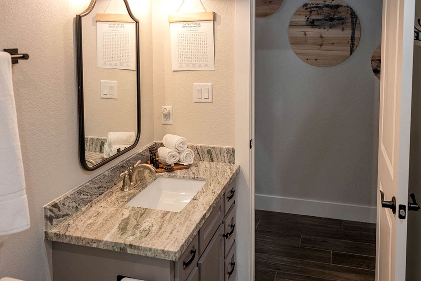A bathroom with a marble sink, a mirror, towels, and a wooden door.
