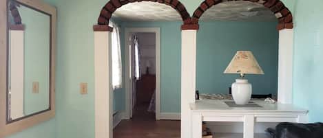 A hallway with a mirror, a lamp, and a staircase leading to another room.
