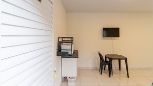 Une pièce comprenant un bureau, une chaise, un téléviseur fixé au mur et une plaque portant le numéro « 13 » sur la porte.