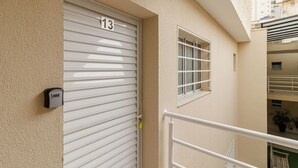 Une porte fermée portant le numéro 13, une petite fenêtre avec une grille en métal et une rambarde de balcon.