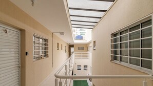 Un couloir étroit avec un puits de lumière, un espace recouvert d’une moquette verte et une rambarde blanche.