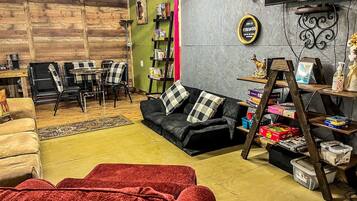 A cozy living room with a sofa, a red chair, a coffee table, a bookshelf, and a TV mounted on the wall.