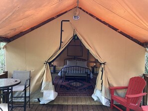 Un hébergement sous tente comprenant un lit, une table et deux chaises.