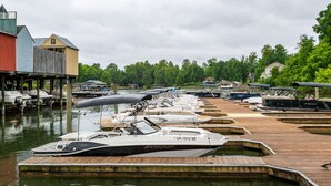 Ein Yachthafen mit vertäuten Booten, Holzstegen und Gebäuden im Hintergrund.