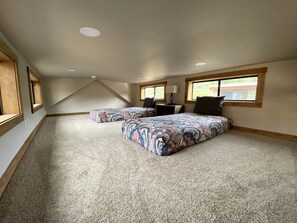 Un dormitorio con una cama grande, una cama más pequeña, una ventana y una rejilla de ventilación en el techo.