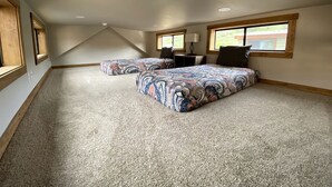 A bedroom with a large bed, a smaller bed, a window, and a ceiling vent.