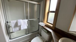 A bathroom with a glass shower enclosure, a toilet, and a sink.