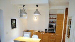 Uma cozinha compacta com uma mesa de jantar, cadeiras, um frigorífico pequeno, um micro-ondas e uma pia.