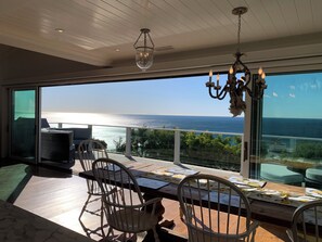 Un balcon avec vue sur la mer, une table avec des chaises et un lustre.