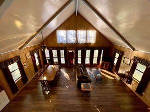 Ein geräumiges Loft mit hohen Decken, Holzwänden, einer Essecke, einer Couch und großen Fenstern.