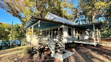 A wooden cabin with a porch, a staircase, and a deck.