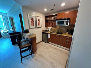 A modern kitchen with wooden cabinets, a built-in microwave, and a countertop with a sink. - Cozy studio in charming Brickell (Miami)