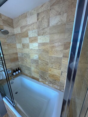 A bathroom with a shower, a bathtub, and a tiled wall. - Cozy studio in charming Brickell (Miami)