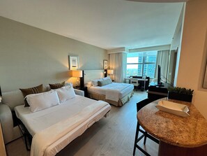 A hotel room with two beds, a desk, a TV, and a view of the city. - Cozy studio in charming Brickell (Miami)