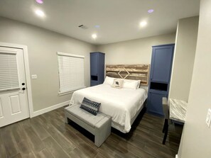 Ein Schlafzimmer mit einem Bett, einer Sitzbank, einem Schreibtisch und einem Kleiderschrank.