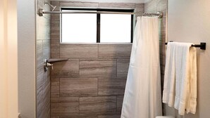A shower with a window, a toilet, and towels on a rack. - Picturesque Cabin Beautifully Designed in Livingston, Texas (Livingston)