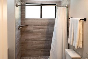 A shower with a window, a toilet, and towels on a rack. - Picturesque Cabin Beautifully Designed in Livingston, Texas (Livingston)