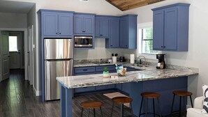 A modern kitchen with blue cabinets, stainless steel appliances, a marble island, and bar stools. - Picturesque Cabin Beautifully Designed in Livingston, Texas (Livingston)