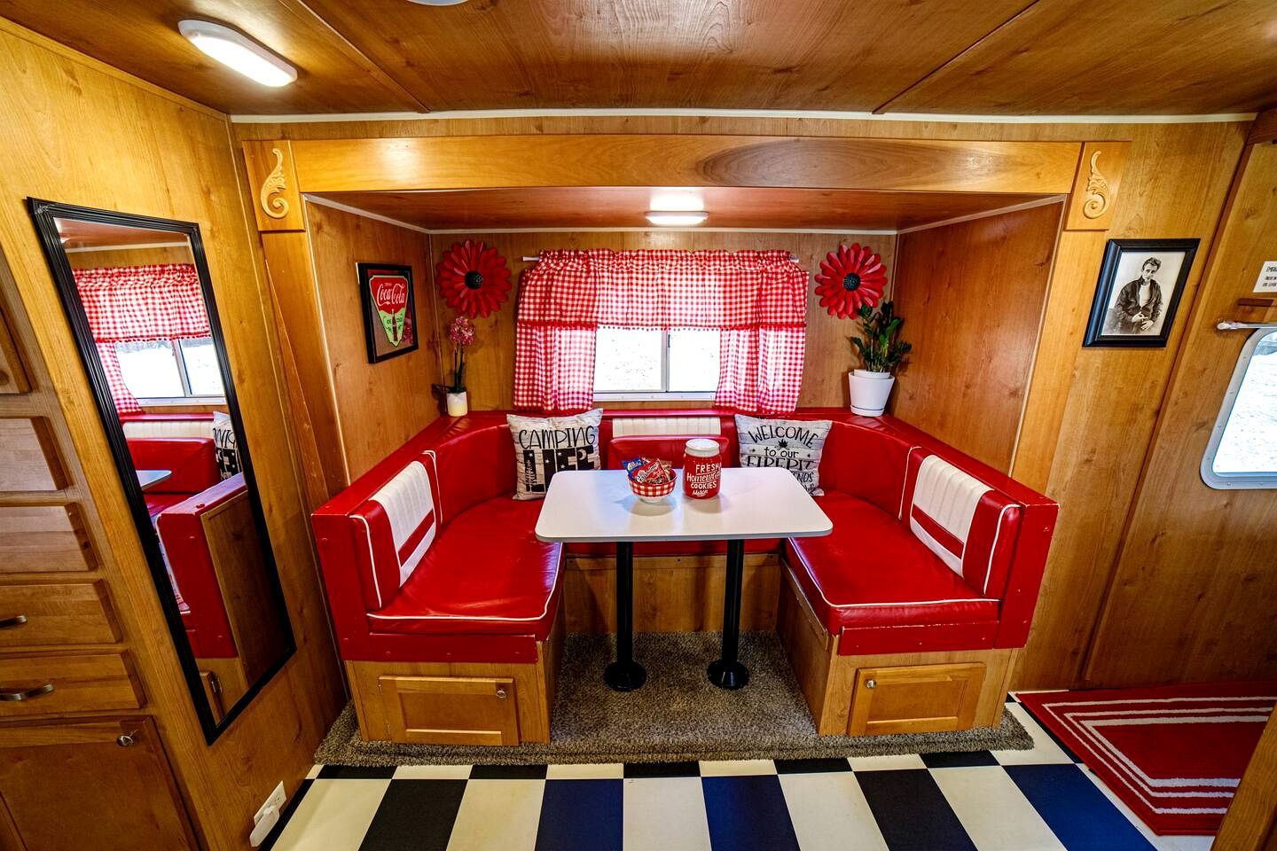 A compact, wood-paneled room with a red and white checkered table and matching bench seating.