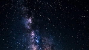 Una carpa bajo un cielo estrellado con la Vía Láctea visible.