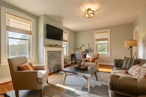 A living room with a fireplace, a flat-screen TV, and a ceiling light fixture.