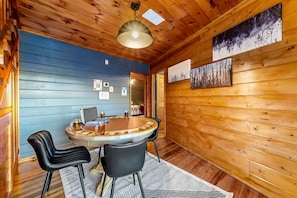 A wooden interior with a round table, two chairs, a hanging light fixture, and wall art. - Spacious Cabin with Game Room, Hot Tub & 3 Decks Near Smoky Mountains, Sevierville, TN (Sevierville)