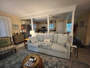 A living room with a sofa, a coffee table, and a view into the kitchen. - Quiet family home- Deck, Trails & Water Sports (Ocean Pines)
