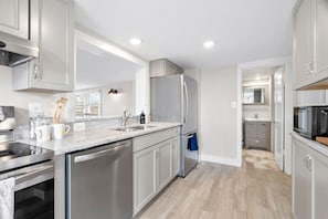 A modern kitchen with stainless steel appliances, a granite countertop, and a view into the adjacent dining area.