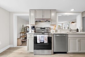 A modern kitchen with stainless steel appliances, white cabinetry, and a large island with a sink.
