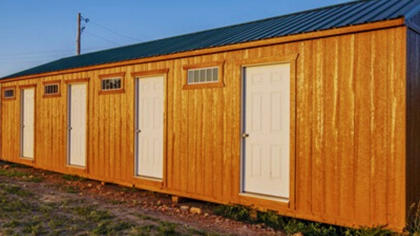 Une rangée de maisons mobiles en bois, avec des portes et des fenêtres blanches.