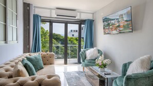 Una sala de estar moderna con sofá, sillones, una mesa de centro y un cuadro de un paisaje urbano.