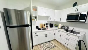 A modern kitchen with white cabinets, a stainless steel refrigerator, a microwave, and a toaster.