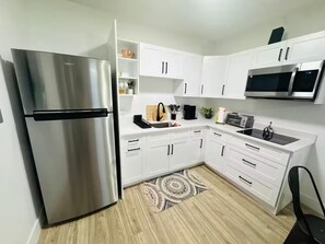 A modern kitchen with white cabinets, a stainless steel refrigerator, a microwave, and a toaster.