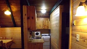 Eine kleine Küche mit Holzwänden, einem Herd und einer Mikrowelle.