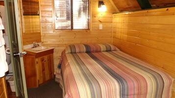 Une petite pièce confortable, avec un lit, une armoire en bois, une fenêtre et une porte.