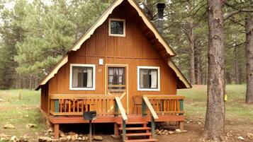 Une cabane en bois avec un porche, une cheminée et le numéro « 12 » sur la porte.