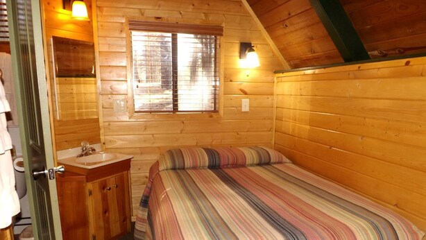 Ein kleiner, gemütlicher Raum mit einem Bett, einem Holzschrank, einem Fenster und einer Tür.