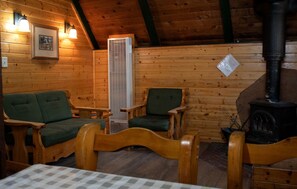 A cozy cabin interior with wooden walls, a fireplace, and two green upholstered chairs. - Relaxing Cabin Perfect to Disconnect and Recharge in Arizona (Flagstaff)