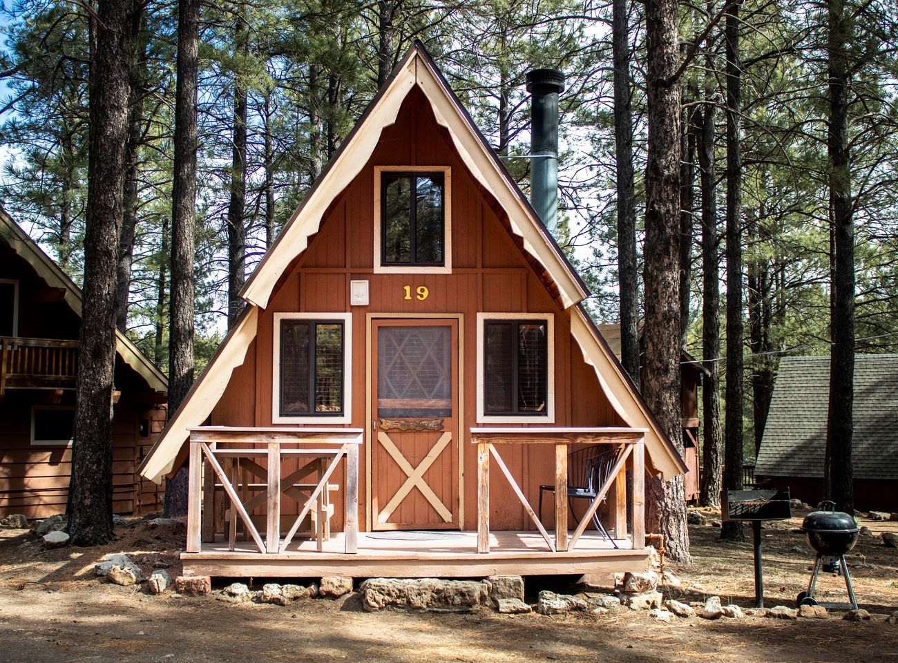 A cabin with a number 19 sign, a porch, and a chimney.