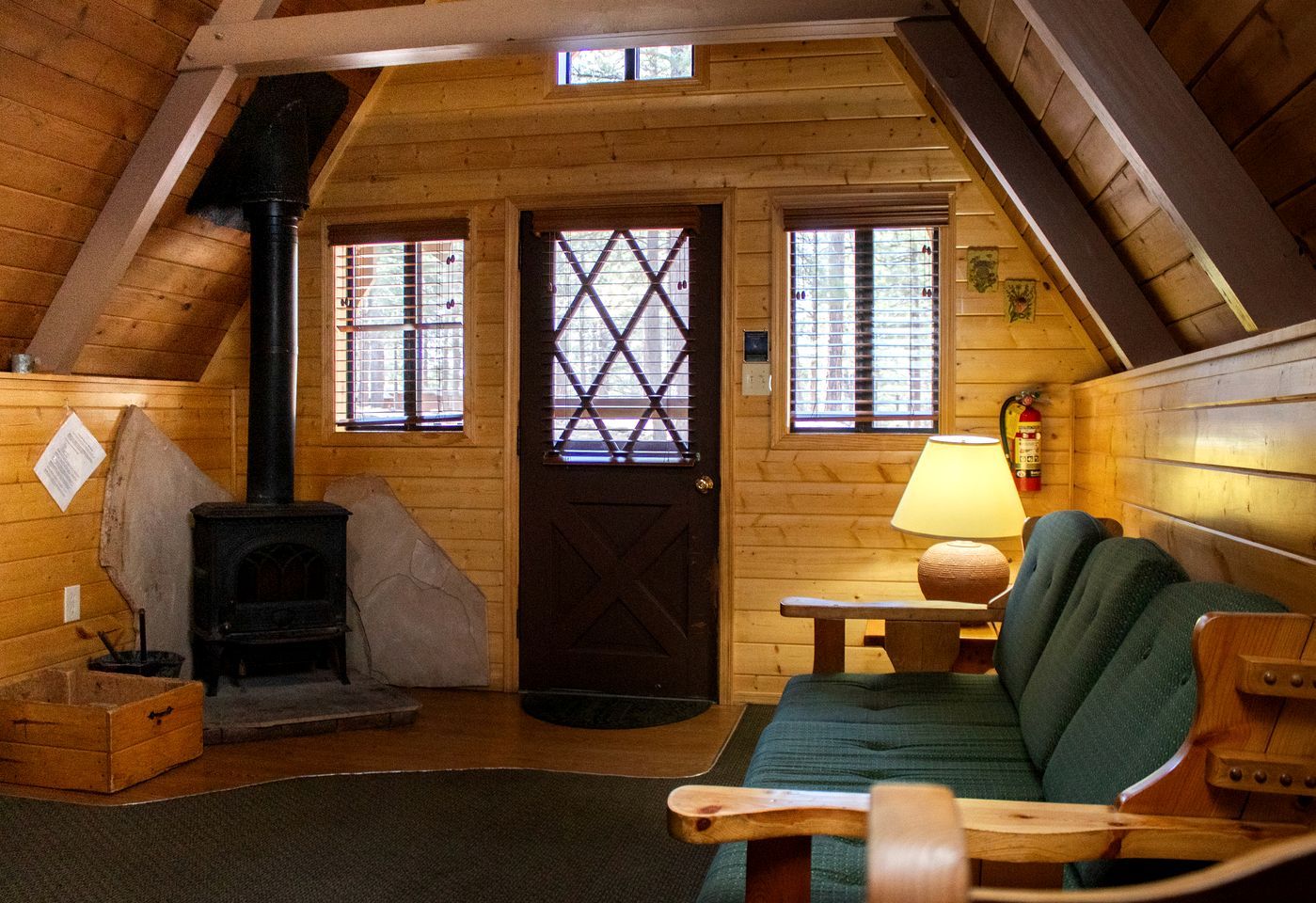L’intérieur d’un chalet accueillant, avec une cheminée, des murs en bois, un canapé et une table.