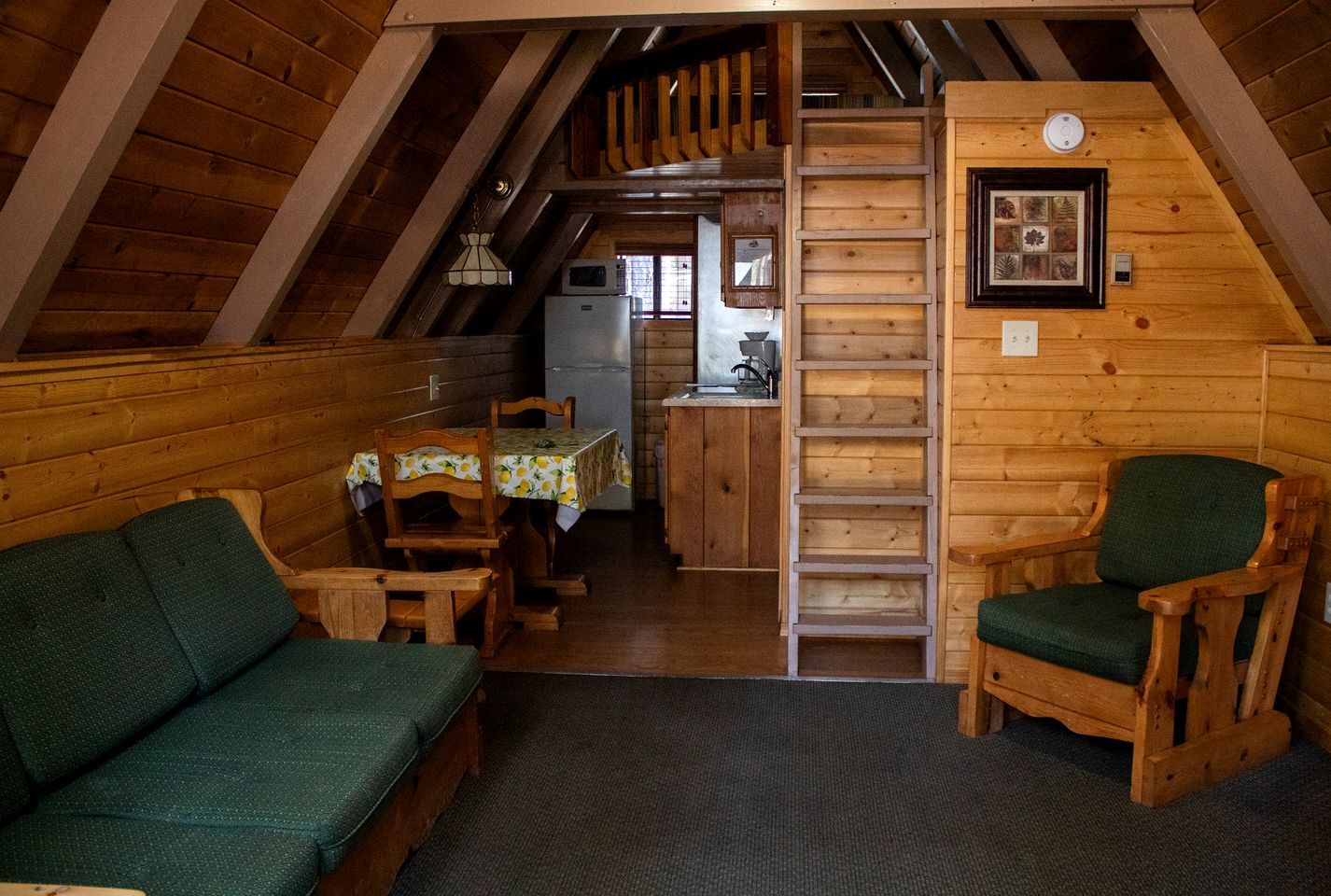 Interior acogedor de una cabaña con comedor, cocina y un altillo.