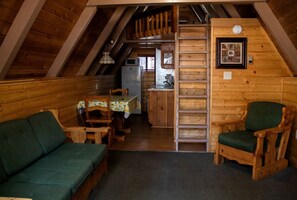Un intérieur de chalet chaleureux comprenant un coin repas, une cuisine et une mezzanine.
