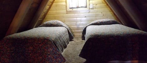 Ein Zimmer mit zwei Betten, einem Fenster und Holzwänden.