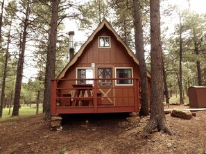 A wooden cabin with a front porch, a chimney, and a window. - Rustic Cabin Perfect for a Family Getaway in Arizona (Flagstaff)