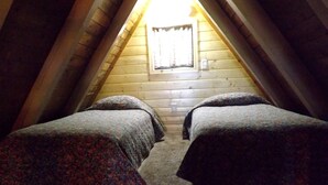 Une chambre avec deux lits, une fenêtre et des murs en bois.