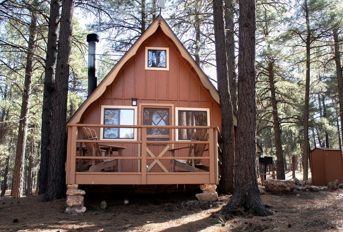 A cabin with a wooden deck, multiple windows, and a chimney.